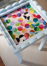 Small table with a colorful polka dot needlepoint canvas top on a neutral background