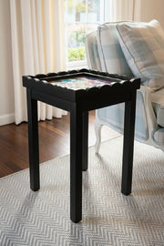 Black needlepoint self finishing table with decorative items in a living room setting